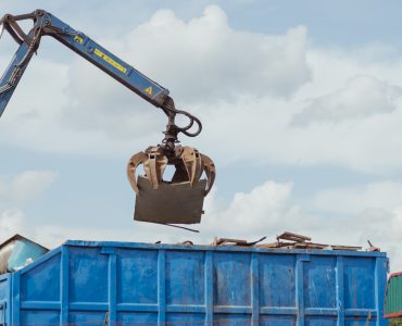 Crane-loading scrap grabber old metal at industrial metal recycling plant. Industrial metal waste recycling